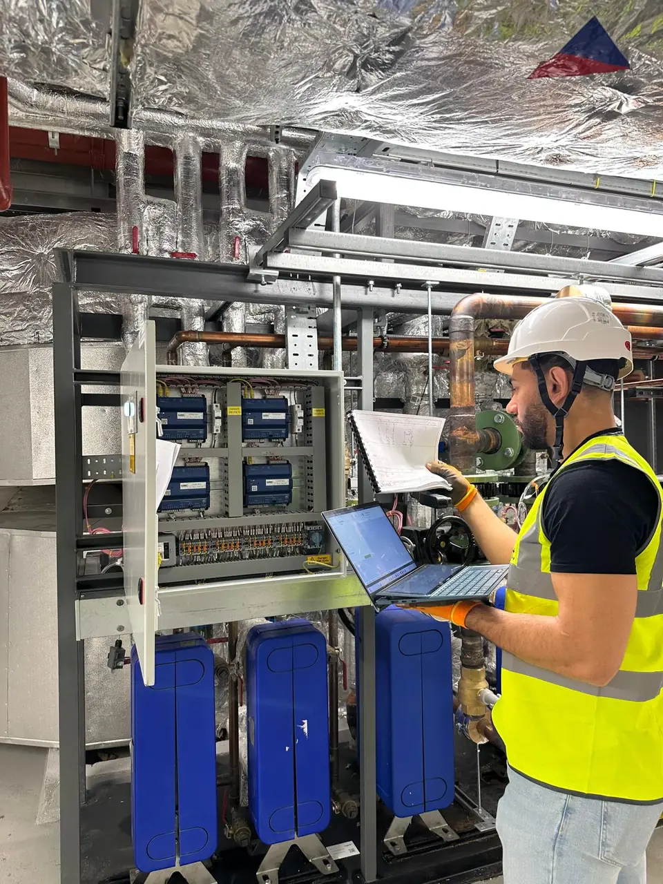 OD Controls engineer reviewing schematics on a live BMS install in a London plant room